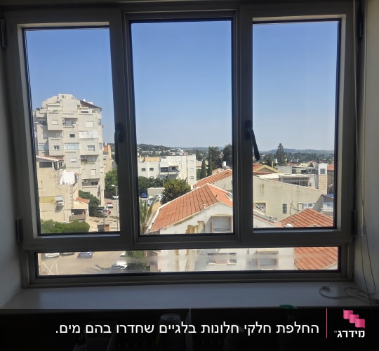 חלון עם תריסים פתוחים ונוף עירוני